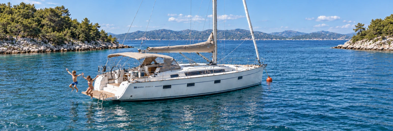 Eine Bavaria Cruiser 51 liegt in einer kroatischen Bucht mit einer kurzen Bugleine an einer orangefarbenen Festmacherboje direkt vor dem Bug; Kinder springen von der Badeplattform am Heck.